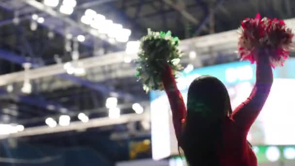 Dame mit roten und grünen Pompons tanzt zur Unterstützung der Sportler — Stockvideo
