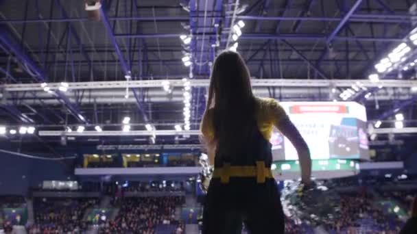 Mädchen mit silbernen Bommeln tanzt unterstützende Spieler auf der Eisbahn — Stockvideo