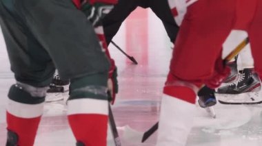 Üniformalı hokey takımları paten sahasında sopalı disk için savaşıyor.