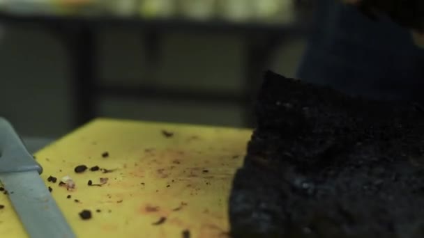 Мужчина нажимает сочное мясо свинины на борту на кухне — стоковое видео