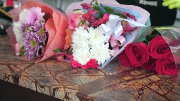 Kvinna kontrollerar vackra blombuketter vid bordet i butiken — Stockvideo