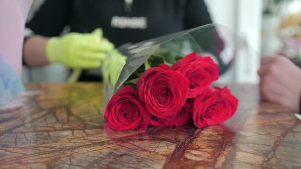 Donna lega steli di rose rosse con nastro dorato a tavola — Video Stock