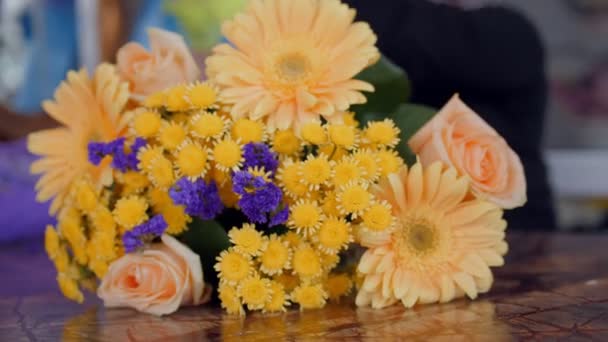 Прекрасный желтый и фиолетовый цветы на столе рядом с женщиной — стоковое видео