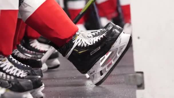 Jugador de hockey en patines uniformados y negros se sienta en el banco — Vídeos de Stock