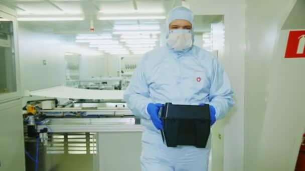 Werknemer in beschermende kostuum en masker draagt zwarte doos — Stockvideo