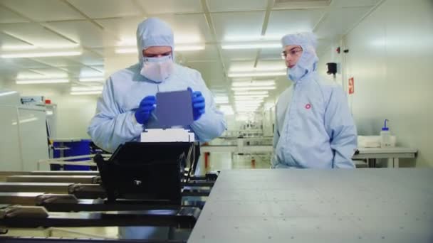 Worker drops down cell of solar panel in plant workshop — Stock Video