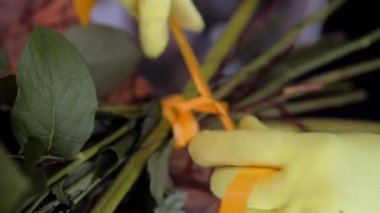 Çiçekçi buketi kurdeleyle bağlar ve dükkanda kenarları keser.