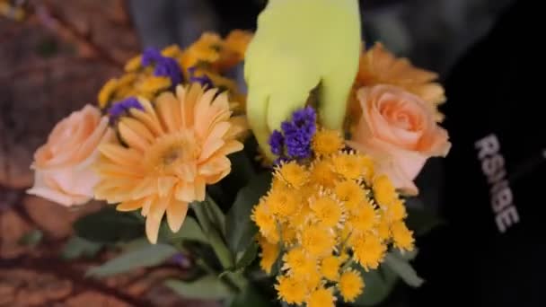 Kwiaciarnia sprawia, bukiet z pomarańczowymi i fioletowymi kwiatami w sklepie — Wideo stockowe