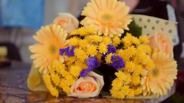 Florist lindar elegant blomma bukett med folie vid bordet — Stockvideo