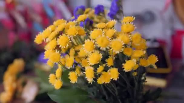 Продавщица делает букет с жёлтыми хризантемами крупным планом — стоковое видео