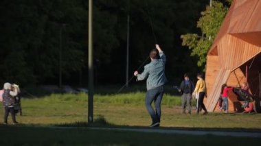 Adam oğluyla uçurtma uçururken, karısı çimenlerde ateş ediyor.