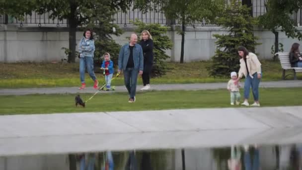 Familia feliz con hija y perro pequeño paseos a lo largo del parque — Vídeos de Stock