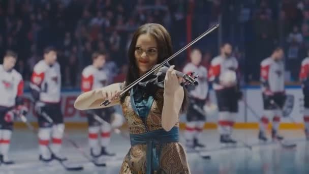 Mulher em vestido dourado e azul toca violino na pista de gelo — Vídeo de Stock