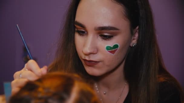 Dáma s lesklým srdcem na tváři aplikuje make-up na dětskou tvář — Stock video