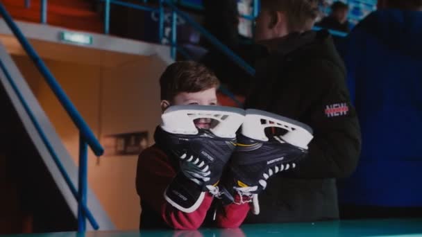 Grappige jongen met schaatsen horloges hockey wedstrijd in het stadion — Stockvideo