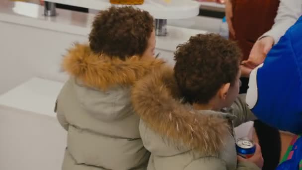 Маленькие мальчики с мамой в куртках покупают газировку в кафе — стоковое видео