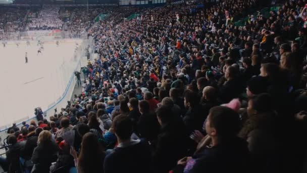 La gente mira el partido de hockey desde lugares de espectadores en el estadio — Vídeos de Stock