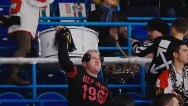 Hombre maduro gira bufanda sobre la cabeza viendo partido de hockey — Vídeos de Stock