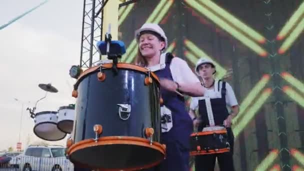 Dame mit weißem Helm spielt große Trommel auf der Bühne beim Festival — Stockvideo