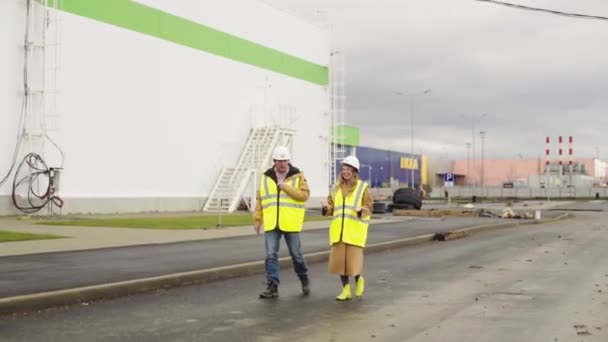 Inženýři ve žlutých vestách kráčejí podél staveniště — Stock video