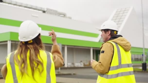 Ingenieur spricht mit Bauarbeiter auf Shopping-Mall-Baustelle — Stockvideo