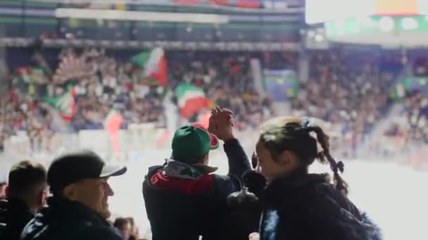 La gente mira partido de hockey apoyar a los jugadores en pista de hielo — Vídeos de Stock