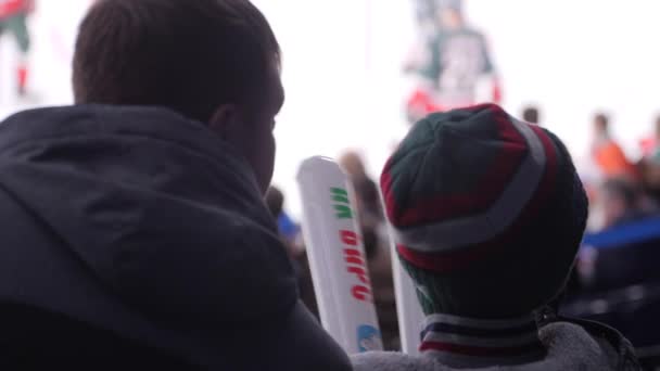 Vater sitzt bei Eishockeyspiel neben Sohn mit weißen Stöcken — Stockvideo