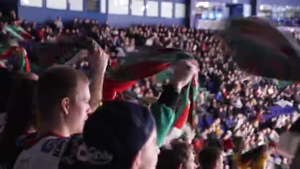Парни поворачивают шарфы с любимым логотипом команды на зрительских местах — стоковое видео