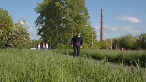 Muž s maskou projíždí skateboard podél silnice v zeleném parku — Stock video