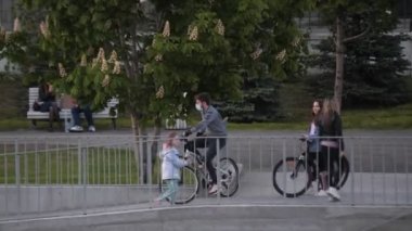 Maskeli genç adam şehir parkında taş rampa boyunca bisiklet sürüyor.