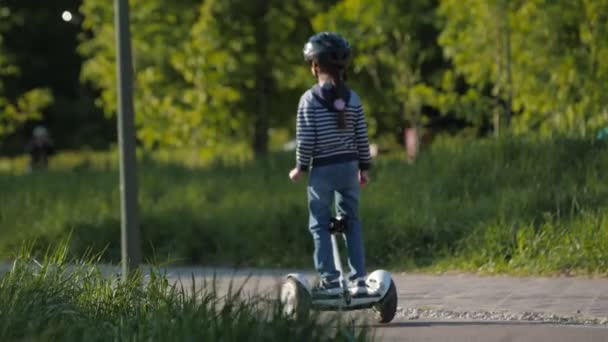 Meisje rijdt hoverboard tijdens moeder helpt zoon met scooter — Stockvideo