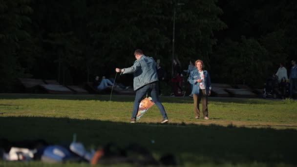 Jovem homem voa pipa com criança pequena no gramado no jardim — Vídeo de Stock