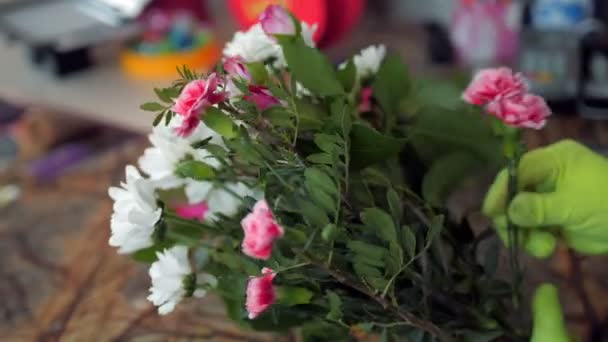 Цветочник делает букет цветов резки зеленой ветви в магазине — стоковое видео