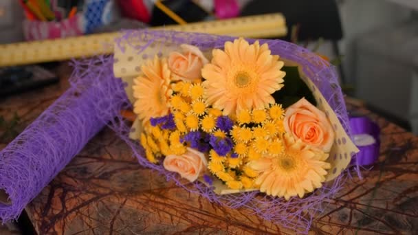 Elegancki bukiet z pomarańczowymi i fioletowymi kwiatami na stole — Wideo stockowe