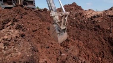 Kazıcı açık inşaat alanında kovayla toprağı kazıyor
