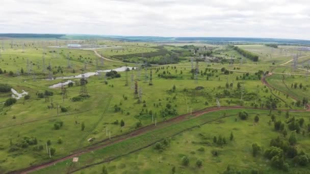 Elektrische zendmasten op groen veld bij rivier — Stockvideo