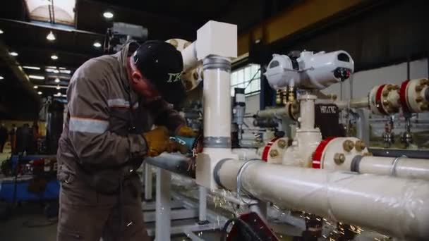 Работник шлифует сварочный шов на современном готовом трубопроводе — стоковое видео