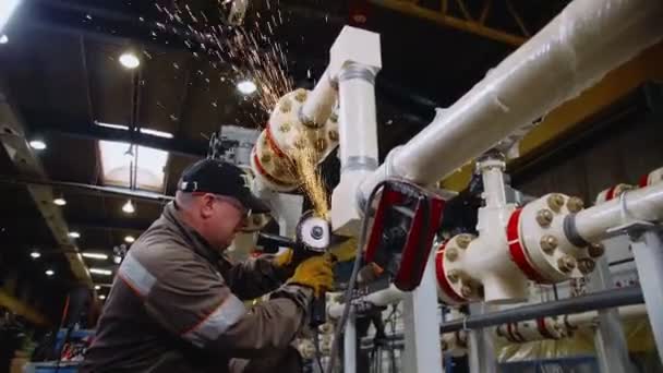 Mens slijpt lasnaad op pijpleiding met handmatig instrument — Stockvideo