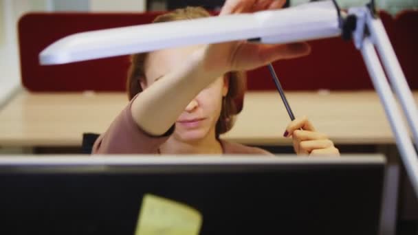 Jovem mulher acende a luz que trabalha no computador no escritório — Vídeo de Stock