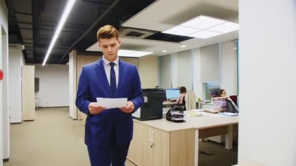 Сотрудник с бумагой общается с коллегой в офисе — стоковое видео