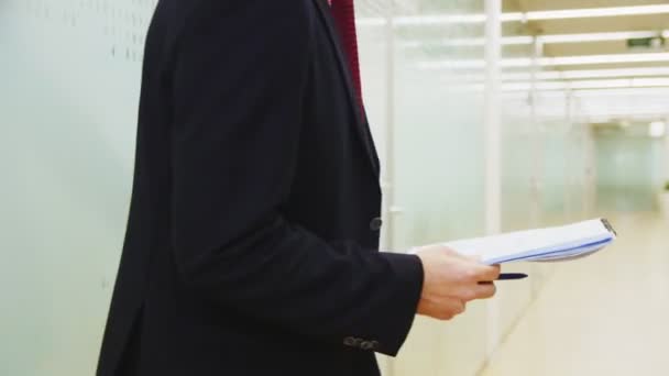 Hombre empanado con cuaderno de papel y bolígrafo camina por el pasillo — Vídeos de Stock