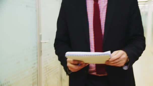 Muž v obleku s kravatou drží zápisník kráčející chodbou — Stock video