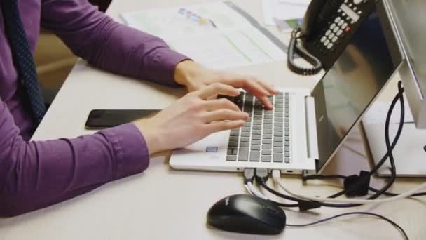 Man types on laptop at comfortable workplace in office — Stock Video