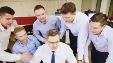 Meslektaşları bilgisayar ekranına bakan adamı alkışlıyor