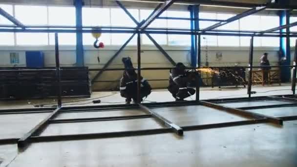 Funcionários moer costuras de soldagem na carcaça na oficina da planta — Vídeo de Stock