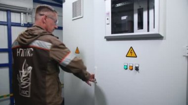 Logo üniformalı elektrikçi dağıtım panosuna geliyor.