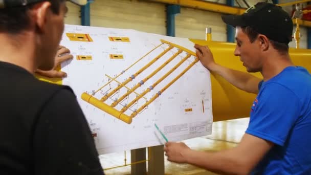 Teknisyenler atölyede boru hattı sisteminin çizimini arıyorlar — Stok video