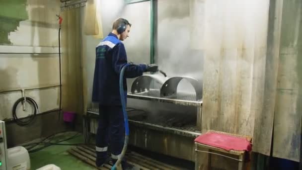 Worker with headphones cleans metal details with steam — Stock Video