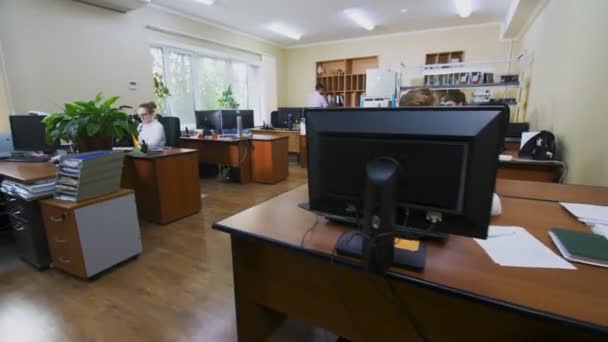 Люди работают в офисе, оборудованном столами и компьютерами — стоковое видео
