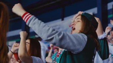 Hokey takımı atkısı ve arkadaşları olan kız sporcuları destekliyor.